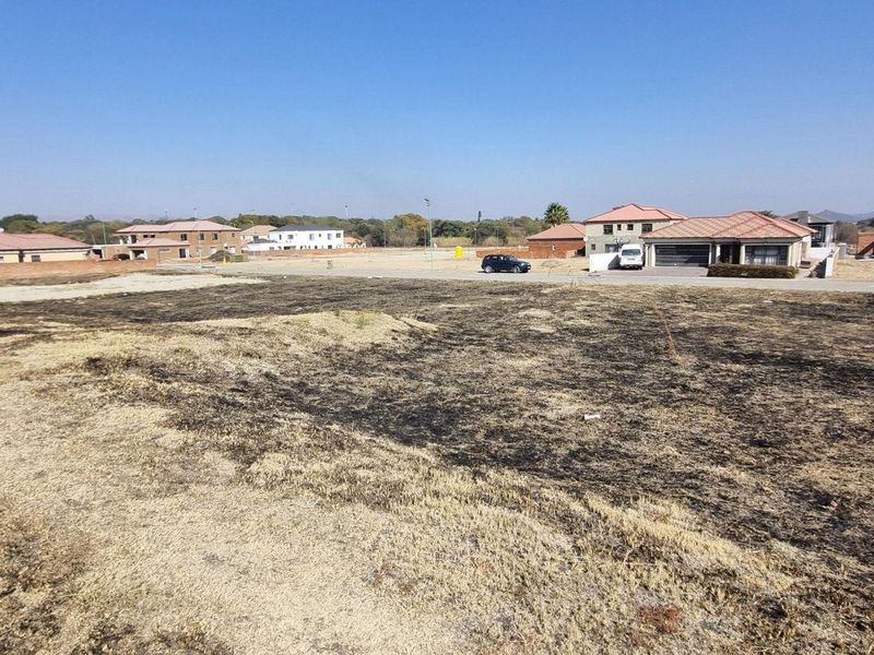 A vacant residential plot of land situated in a developed neighborhood with surrounding houses.