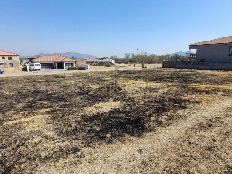 A vacant residential plot of land situated in a developed neighborhood, featuring open space and surrounding boundary walls.