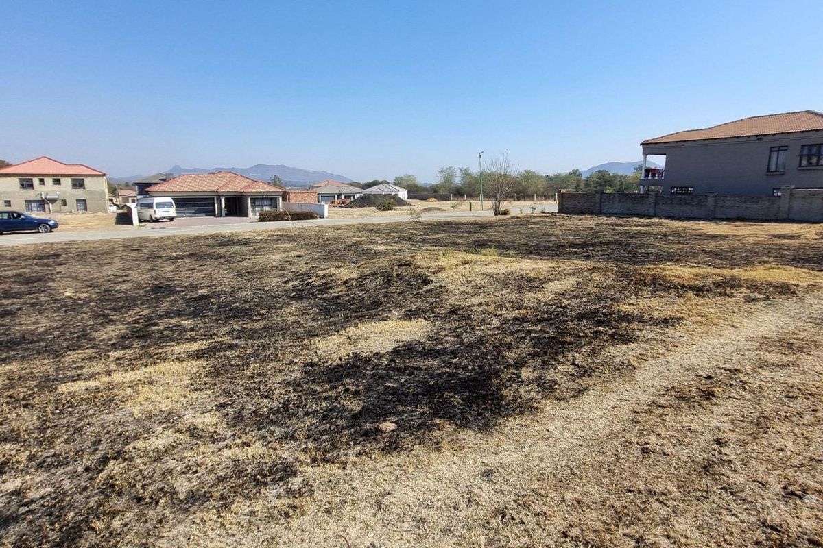 A vacant residential plot of land situated in a developed neighborhood, featuring open space and surrounding boundary walls.