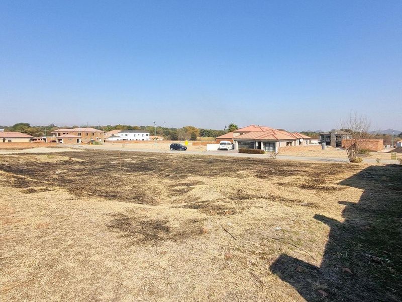 A vacant residential plot featuring a boundary wall and open land, situated in a developed neighborhood.