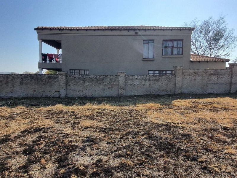 View of the rear elevation of the property featuring a brick boundary wall and a covered balcony area.