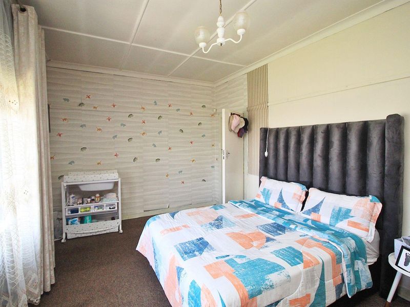 A bedroom featuring carpeted flooring and a central light fixture, currently showing signs of wear on the wall finishes.