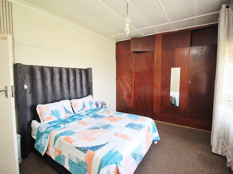 A bedroom featuring built-in wooden wardrobes and carpeted flooring, offering a functional space with potential for cosmetic updates to enhance its appeal.