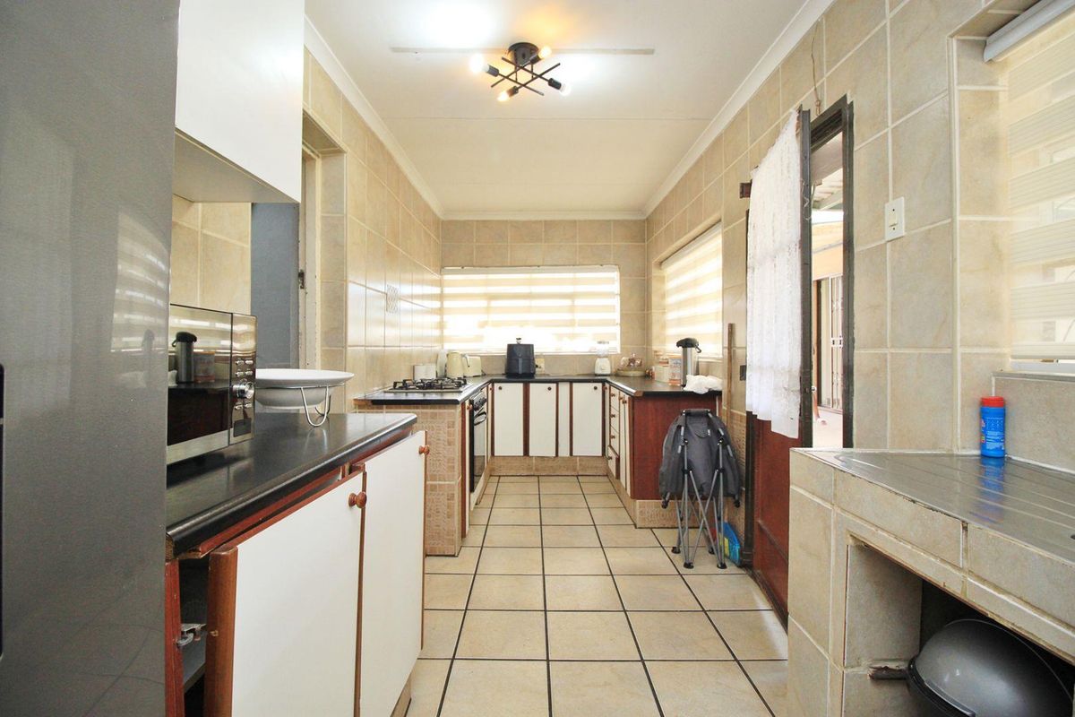 A functional kitchen featuring tiled walls and floors, built-in cabinetry, stone countertops, and a gas hob with an integrated oven.