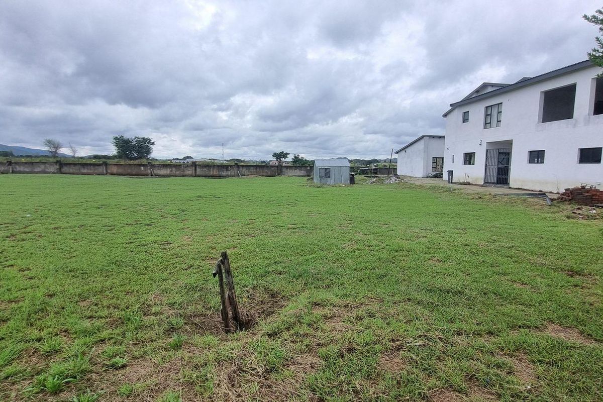 Spacious rear yard featuring a large grass lawn, perimeter wall, and a small outbuilding structure.