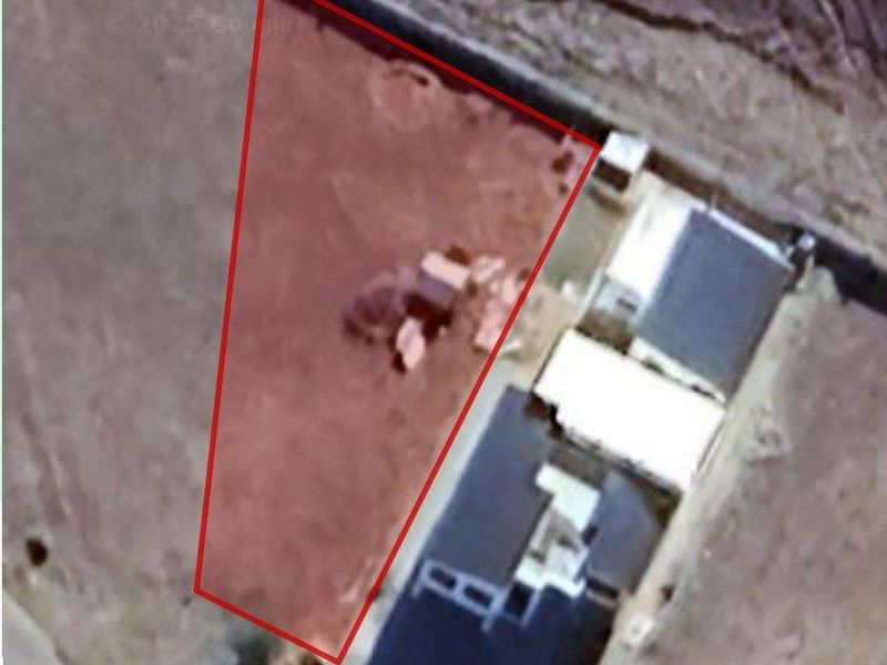 Aerial view of a vacant residential plot outlined in red, showing the land boundaries and surrounding area.