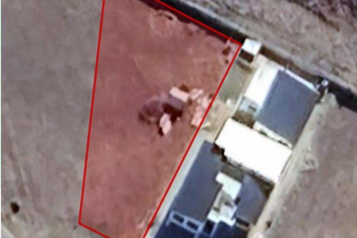 Aerial view of a vacant residential plot outlined in red, showing the land boundaries and surrounding area.