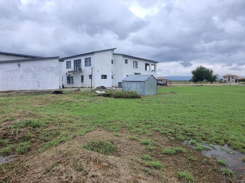 A view of the rear yard area featuring a grass lawn and a small metal storage shed, with the main building structure visible.