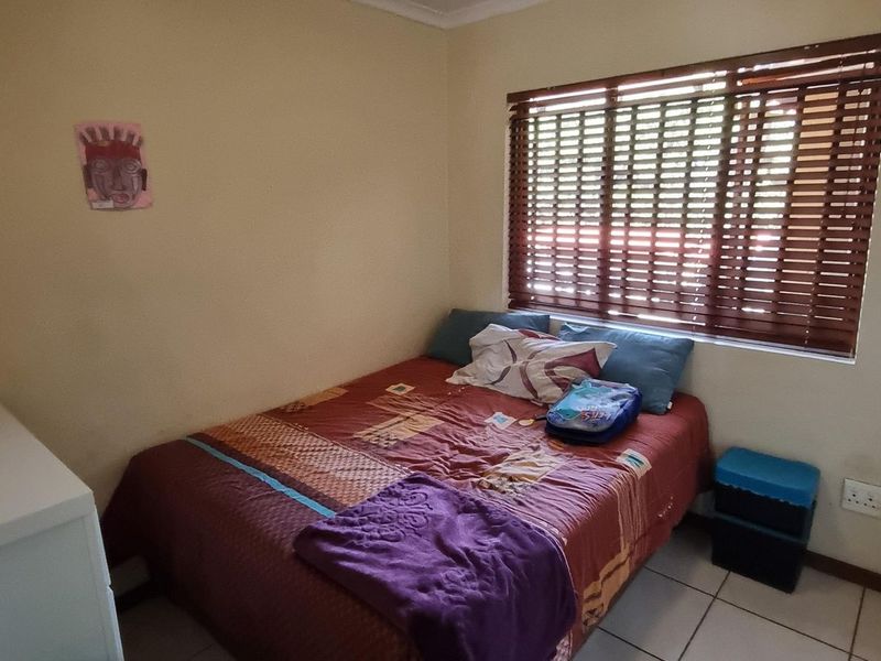 A functional bedroom featuring tiled flooring, a built-in wardrobe, and venetian blinds, providing a neutral space ready for personalization.