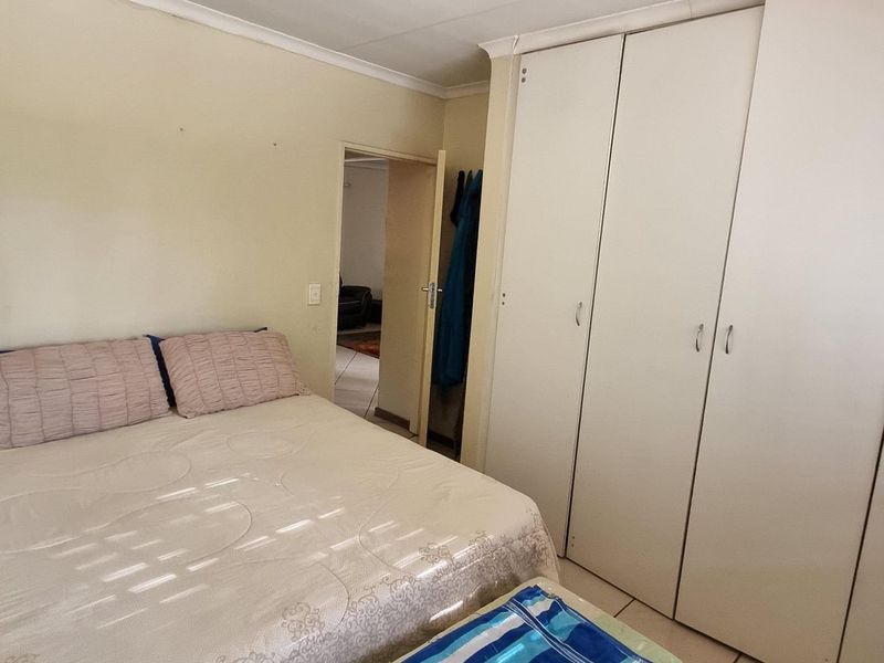 A functional bedroom featuring built-in cupboards and tiled flooring, offering a neutral space ready for personalization.