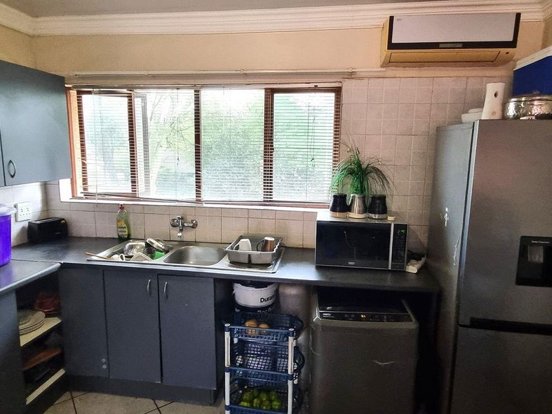 A functional kitchen featuring dark cabinetry, a double sink, tiled backsplash, and an integrated extractor fan, providing a practical workspace with room for updates.
