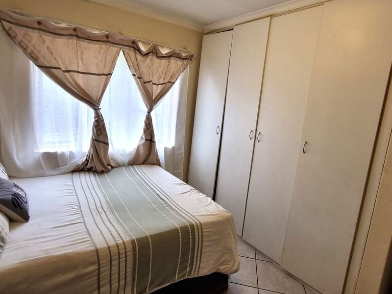 A functional bedroom featuring built-in cupboards and tiled flooring, offering a practical layout with natural light from the window.