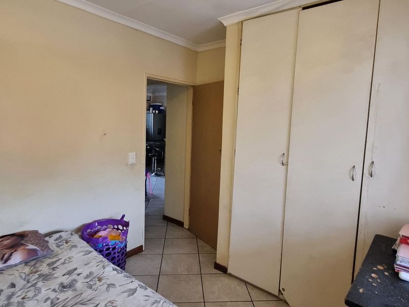 A bedroom featuring built-in cupboards, tiled flooring, and coved ceilings, requiring some cosmetic updates to refresh the space.