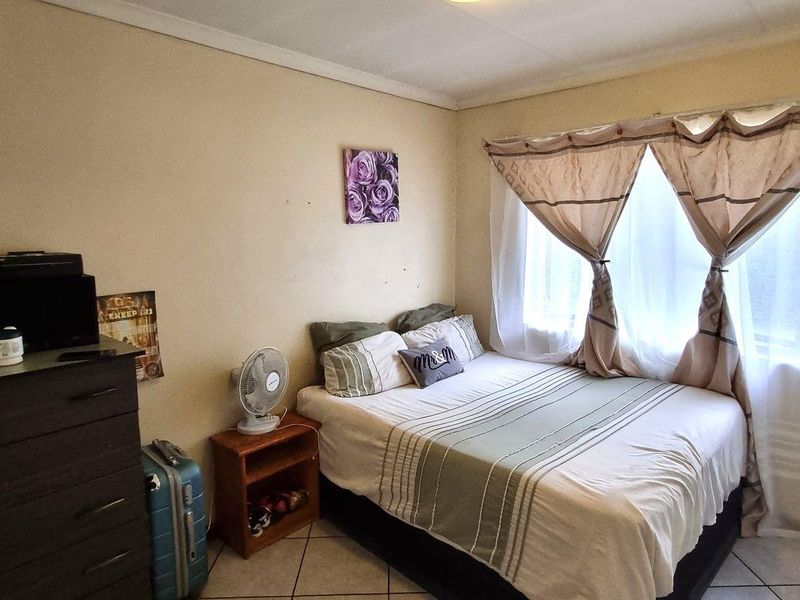 A functional bedroom featuring tiled flooring and a built-in wardrobe, offering a practical layout with natural light from the window.