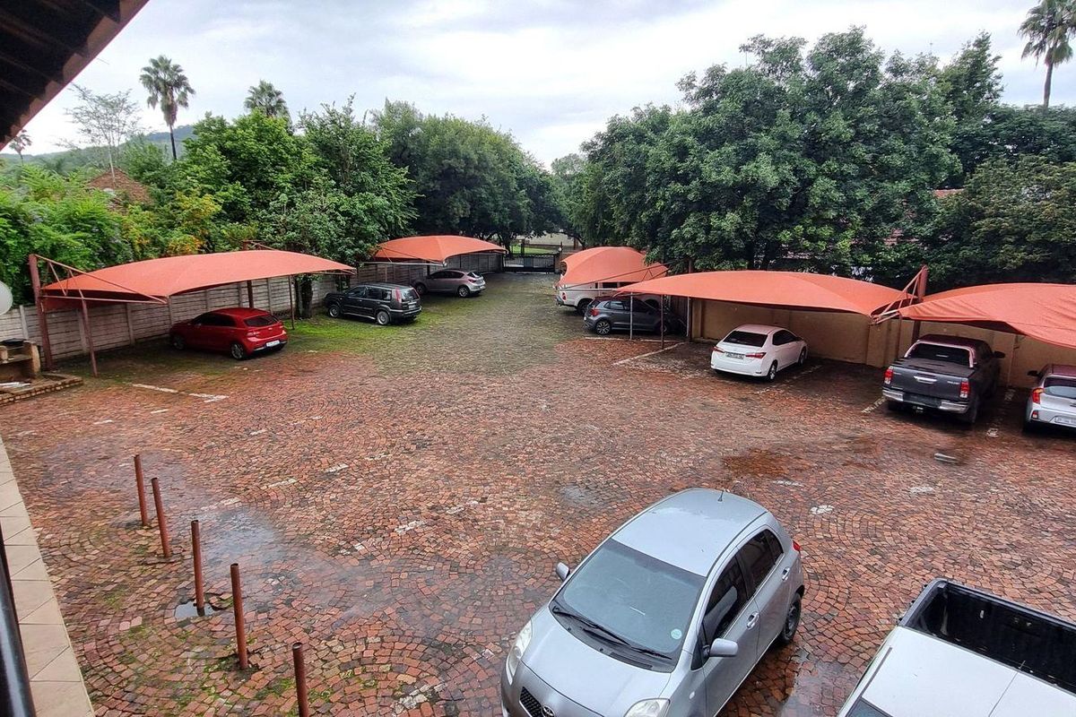 An outdoor parking area featuring multiple shade cloth carports and a paved driveway surface within a residential apartment complex.
