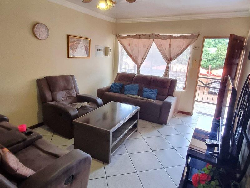 A living room featuring tiled flooring, a ceiling fan, and direct access to an outdoor area through a standard door.