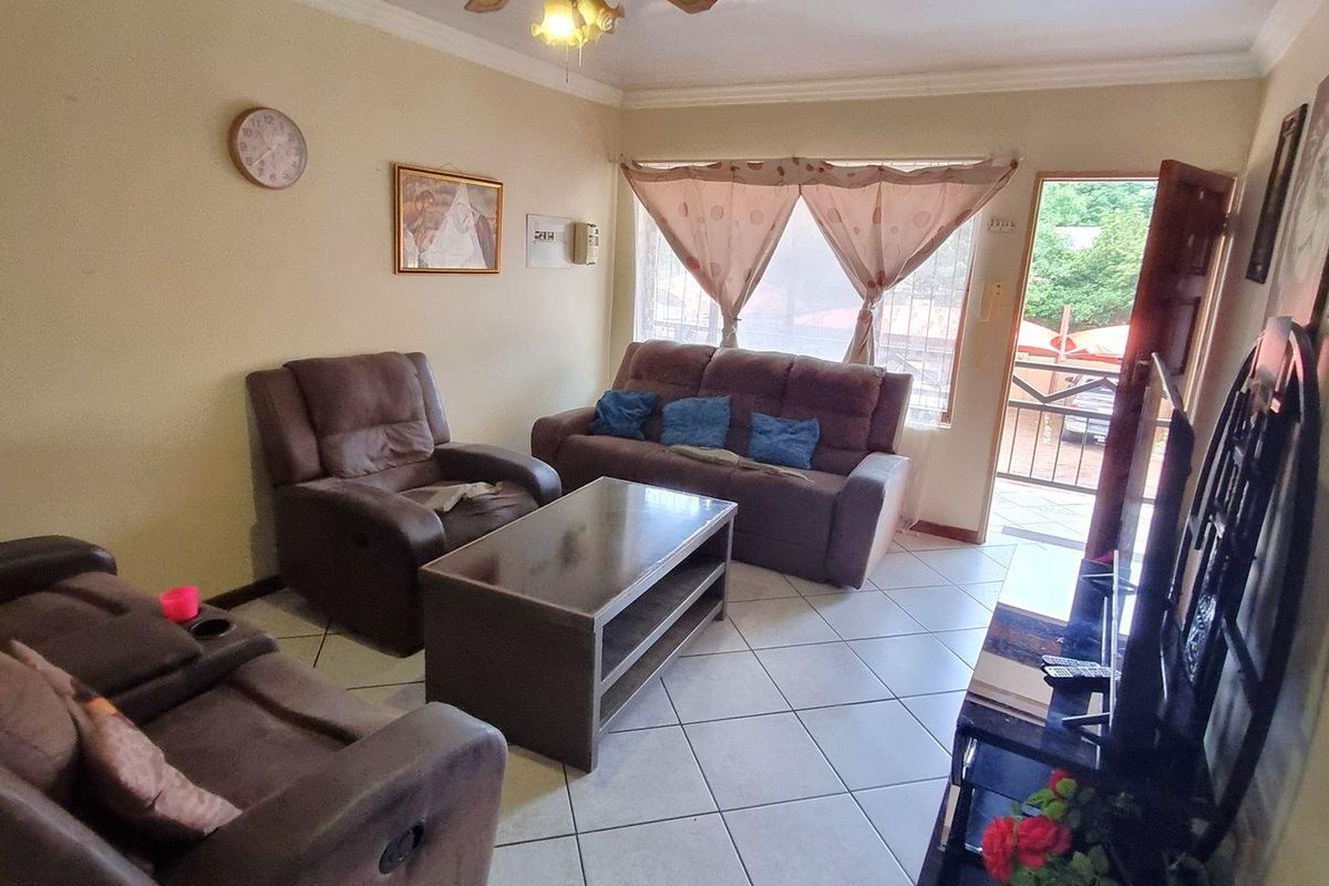 A living room featuring tiled flooring, a ceiling fan, and direct access to an outdoor area through a standard door.