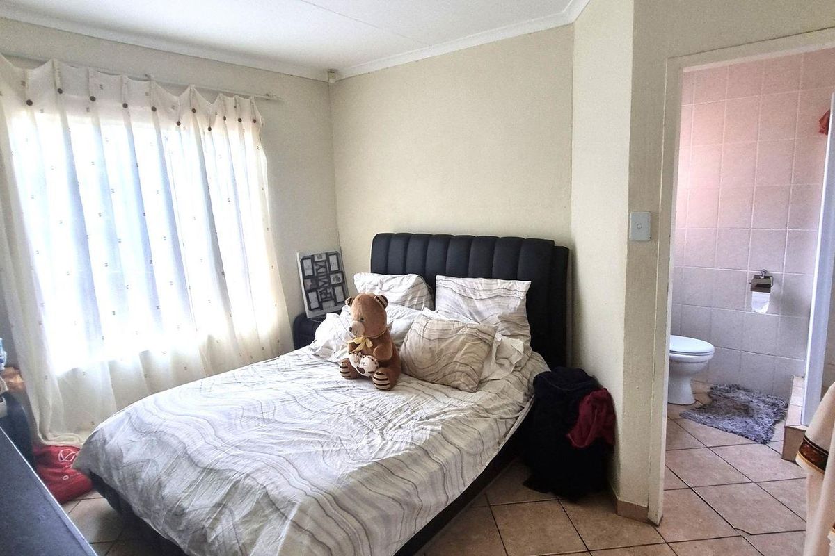 A bedroom featuring tiled flooring and an en-suite bathroom with tiled walls and a toilet.