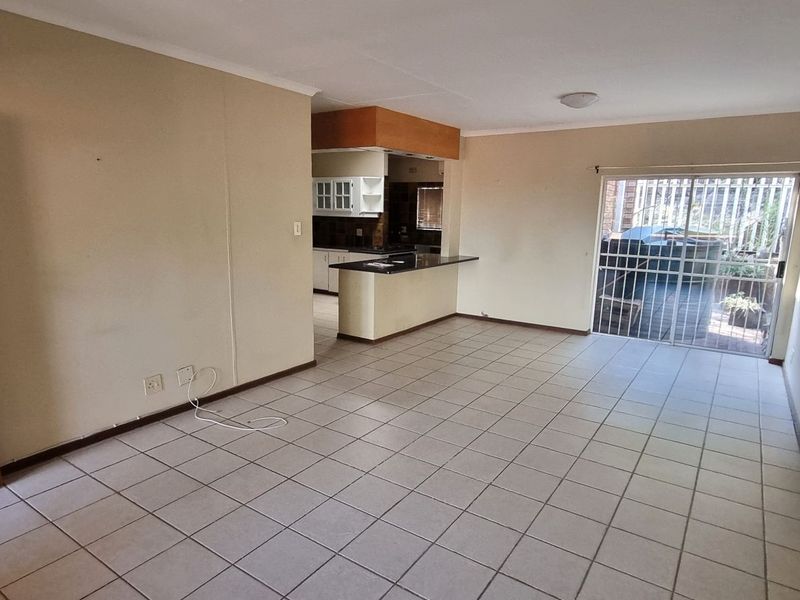 Spacious open-plan living area featuring tiled flooring, a breakfast bar connecting to the kitchen, and sliding door access to an outdoor patio.