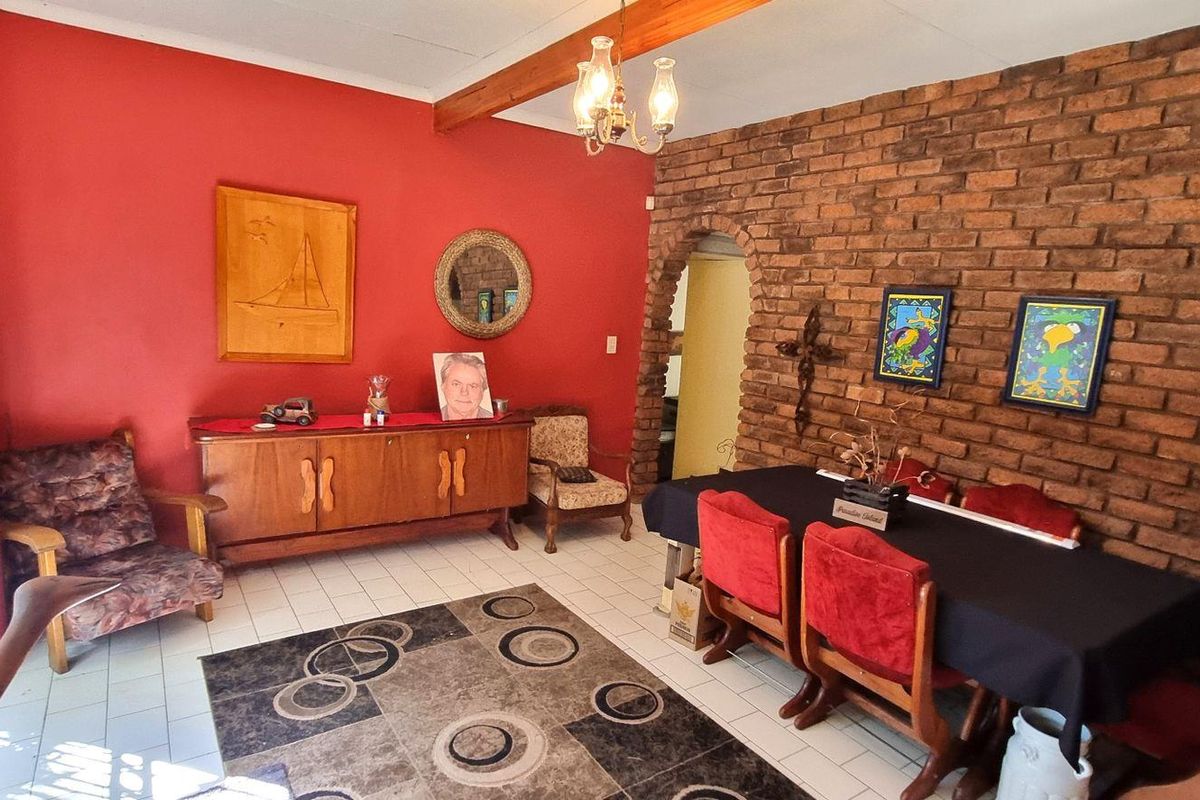 A dining and living area featuring a prominent exposed brick feature wall, tiled flooring, and sliding glass doors providing natural light.