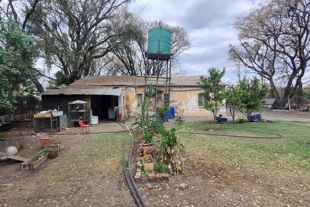 Rear view of the property showing a garden area, a raised water tank, and the rear building facade with visible signs of wear.