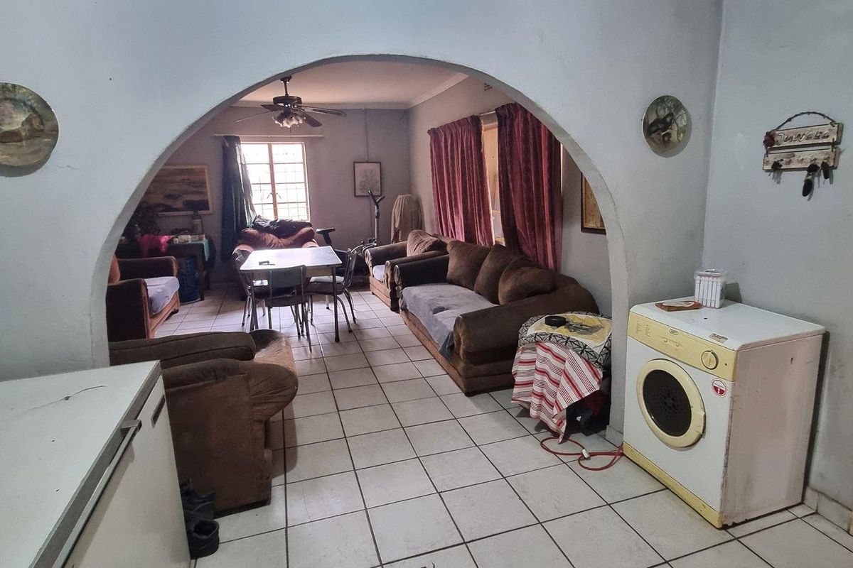 Living area featuring tiled flooring and a distinctive arched doorway connecting to an adjacent space.