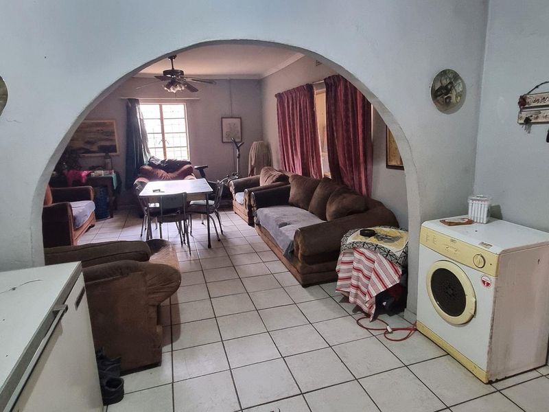 Living area featuring tiled flooring and a distinctive arched doorway connecting to an adjacent space.