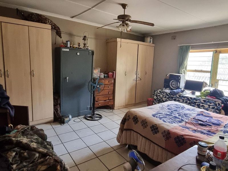 A bedroom featuring built-in cupboards, tiled flooring, and a ceiling fan, requiring cosmetic updates to improve its overall condition and appeal.