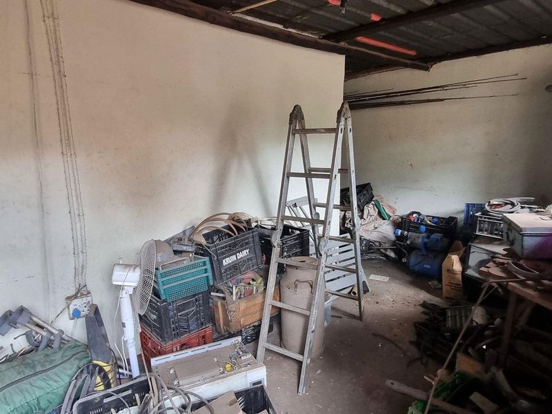 A cluttered garage space featuring exposed roof rafters and basic electrical infrastructure, requiring significant clearing and maintenance to restore functionality.
