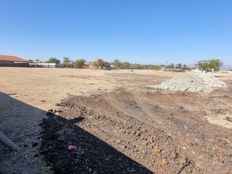 A vacant residential plot featuring cleared land and a boundary wall, offering a blank canvas for new construction in a developed neighborhood.