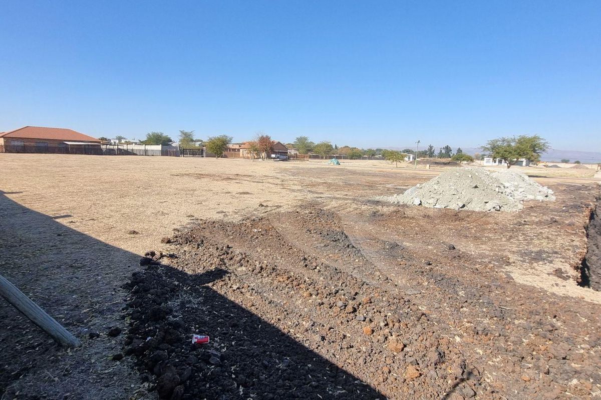 A vacant residential plot featuring cleared land and a boundary wall, offering a blank canvas for new construction in a developed neighborhood.