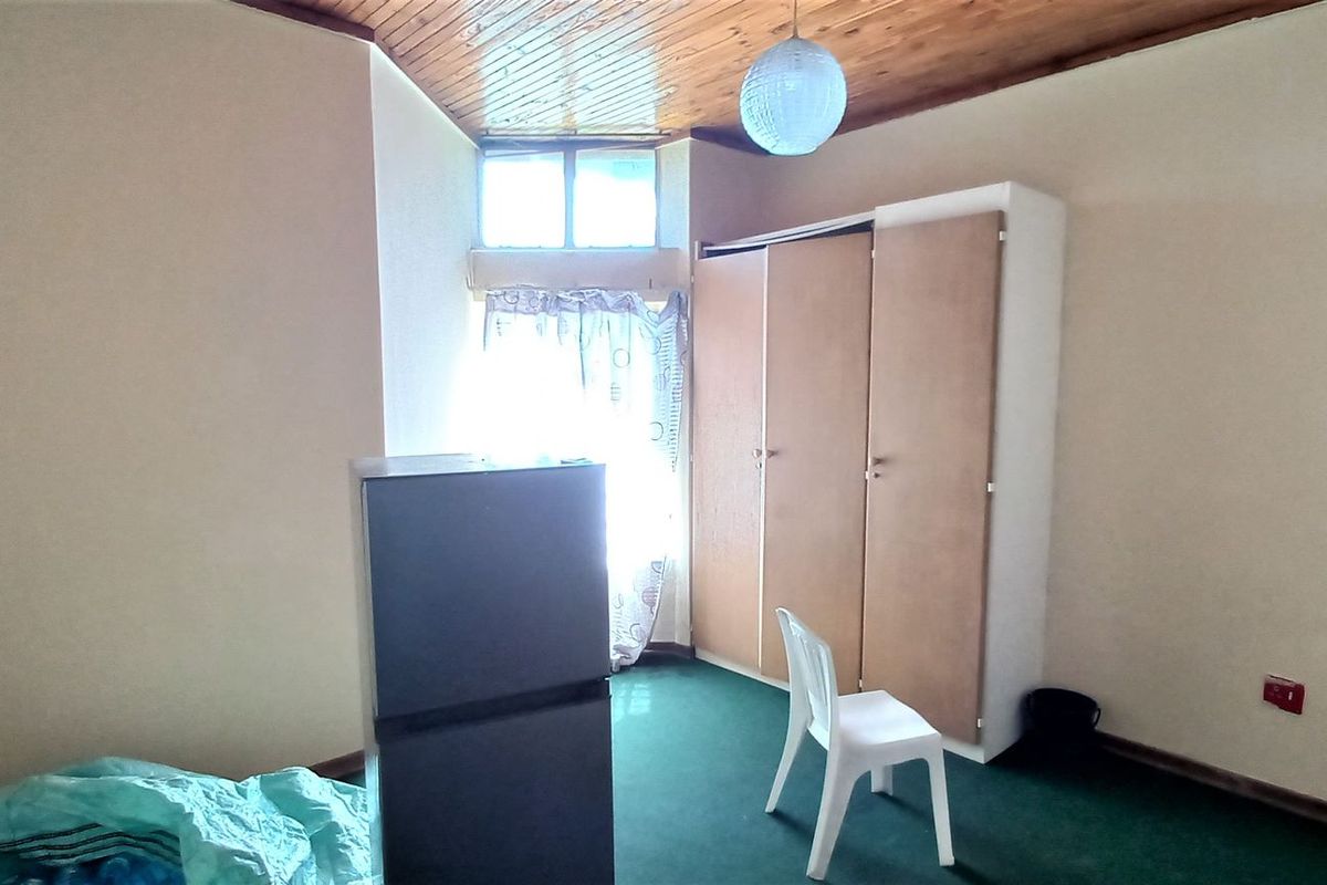 A bedroom featuring a timber-clad ceiling, built-in wardrobe, and carpeted flooring, offering a functional space ready for personalization.