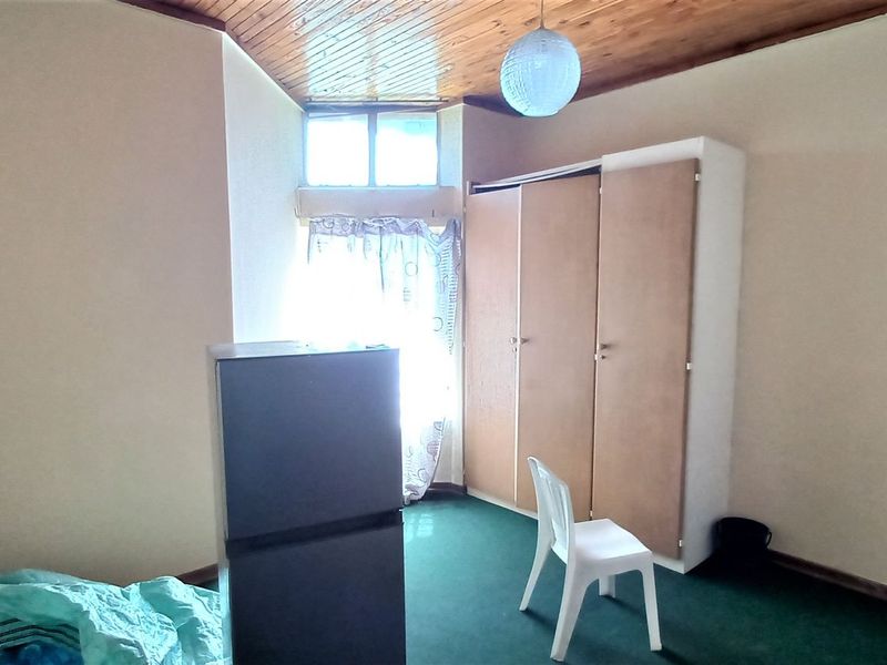 A bedroom featuring a timber-clad ceiling, built-in wardrobe, and carpeted flooring, offering a functional space ready for personalization.