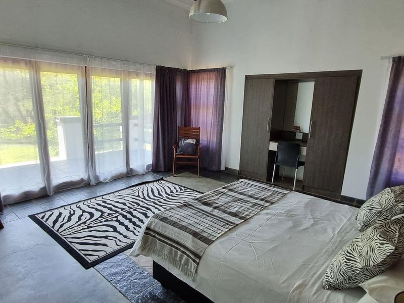 Spacious bedroom featuring built-in wardrobes, tiled flooring, and large sliding glass doors providing direct access to the outdoor area.