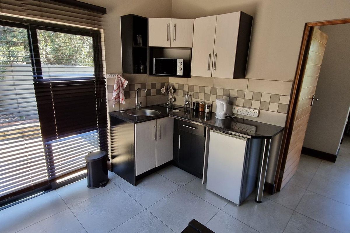 Compact kitchenette featuring modern cabinetry, granite countertops, tiled backsplash, and direct access to an outdoor patio area through sliding glass doors.