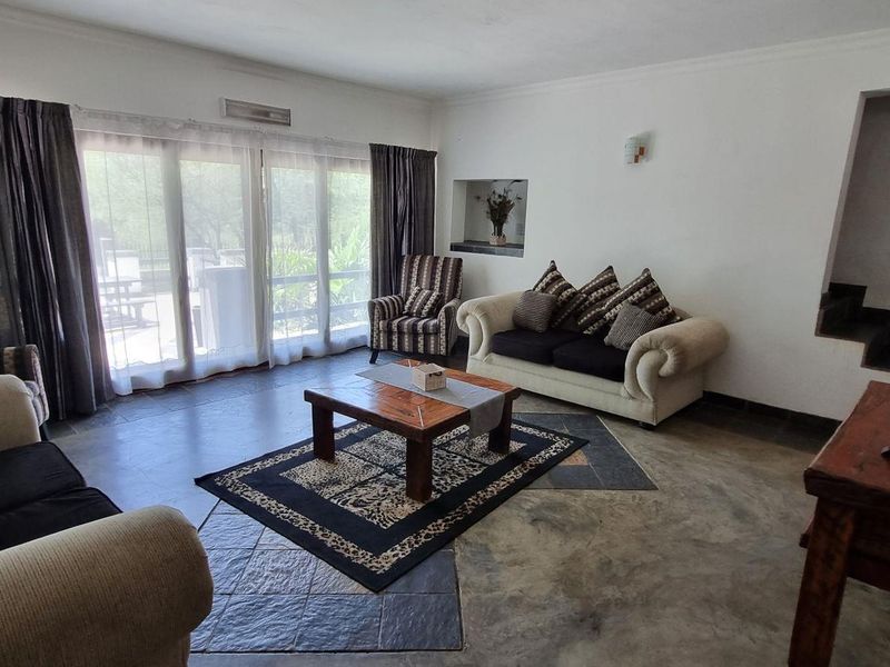 Spacious living room featuring tiled flooring, an exposed brick accent wall, a recessed wall niche, and large sliding glass doors leading to the exterior.