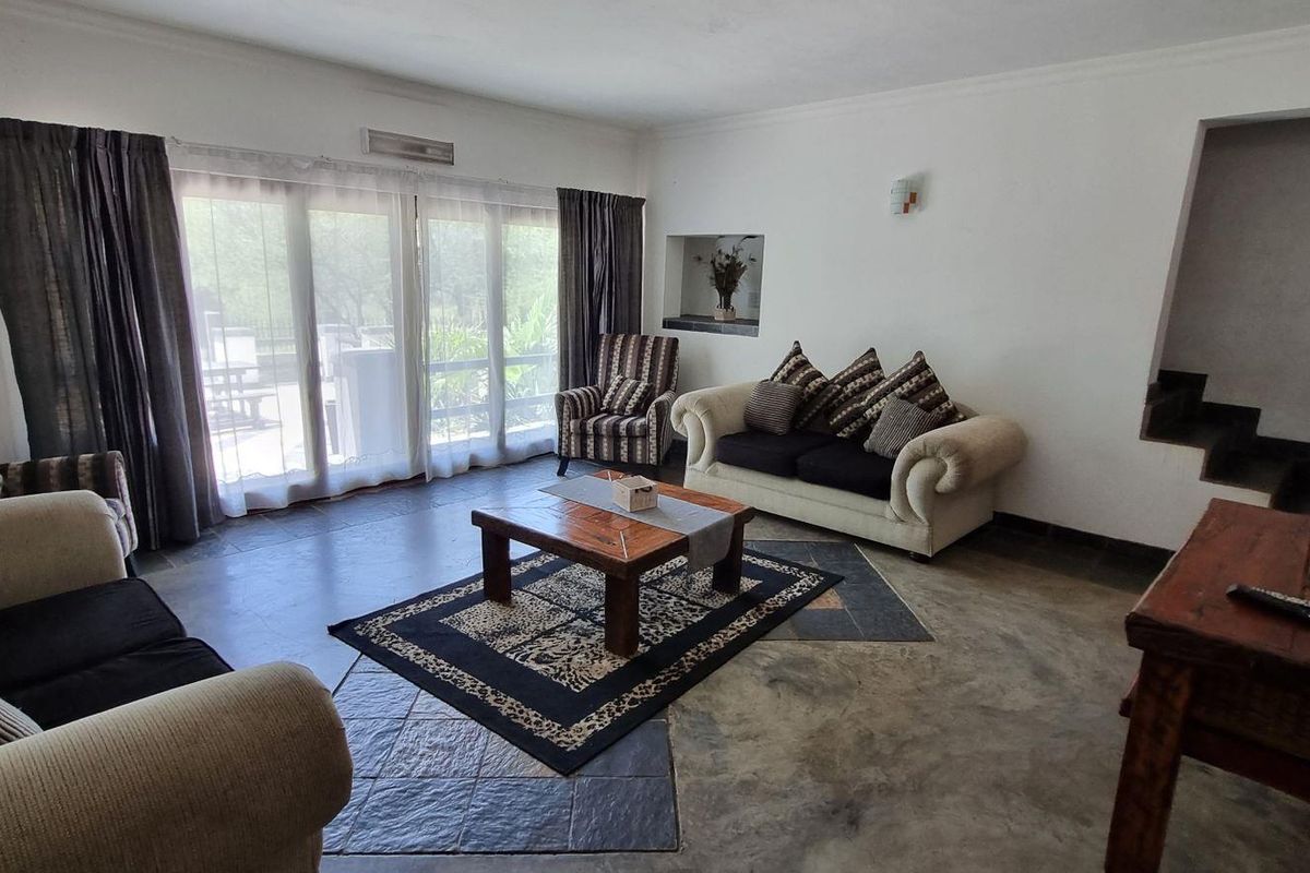 Spacious living room featuring tiled flooring, an exposed brick accent wall, a recessed wall niche, and large sliding glass doors leading to the exterior.