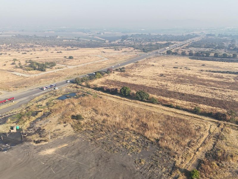 Aerial view of a large commercial land parcel adjacent to a main road, featuring expansive open terrain and clear access routes.