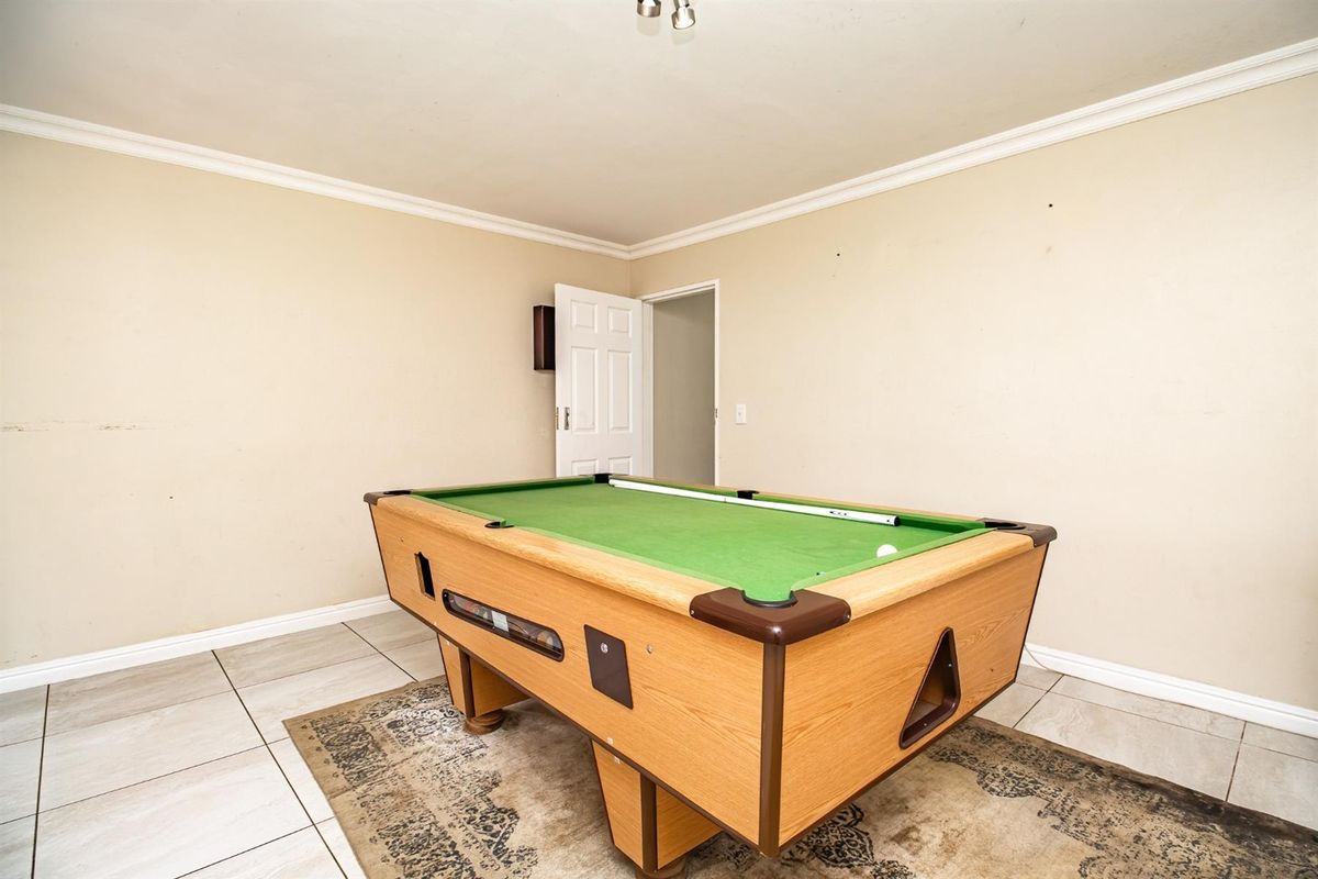 A versatile room featuring neutral tiled flooring and crown molding, currently utilized as a recreation space.