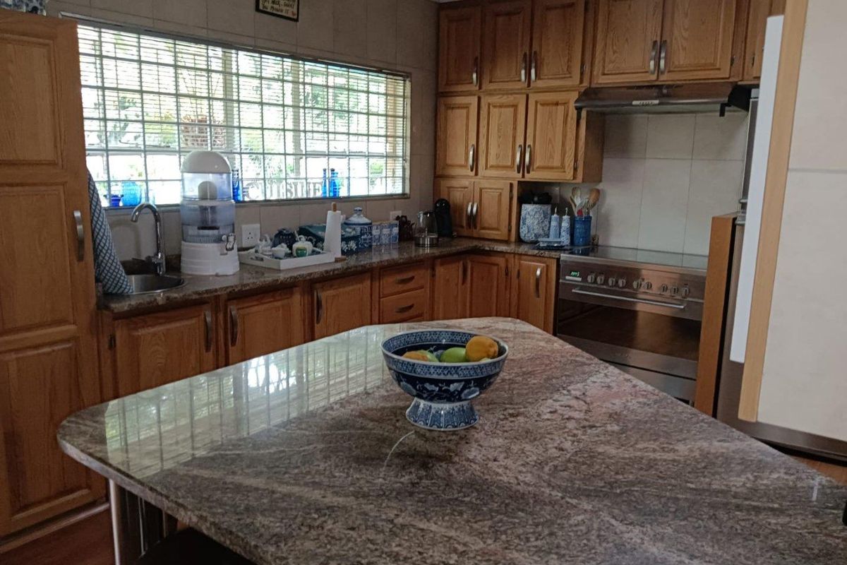 A functional kitchen featuring wooden cabinetry, granite countertops, a central island, and built-in stainless steel appliances.