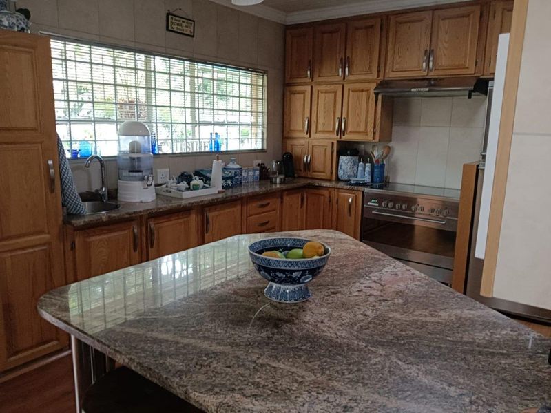 A functional kitchen featuring wooden cabinetry, granite countertops, a central island, and built-in stainless steel appliances.
