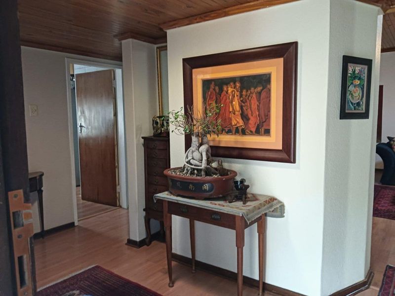 A functional hallway featuring warm timber ceiling paneling and laminate flooring, providing access to adjacent rooms within the home.