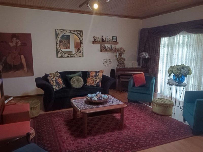 A cozy living room featuring a timber-paneled ceiling, laminate flooring, and a large sliding glass door providing natural light.