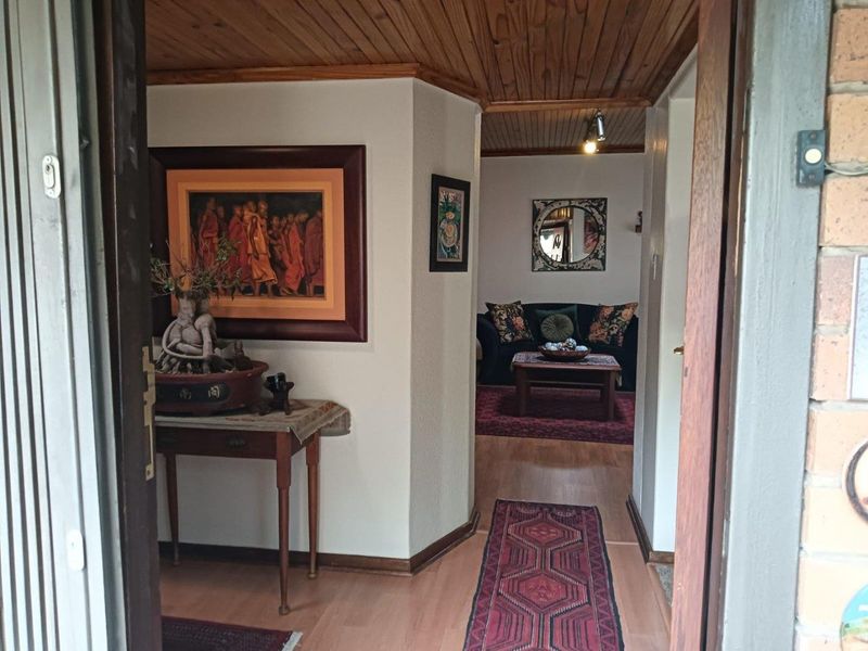 Entrance foyer featuring timber ceiling and laminate flooring, leading into an open-plan living area.