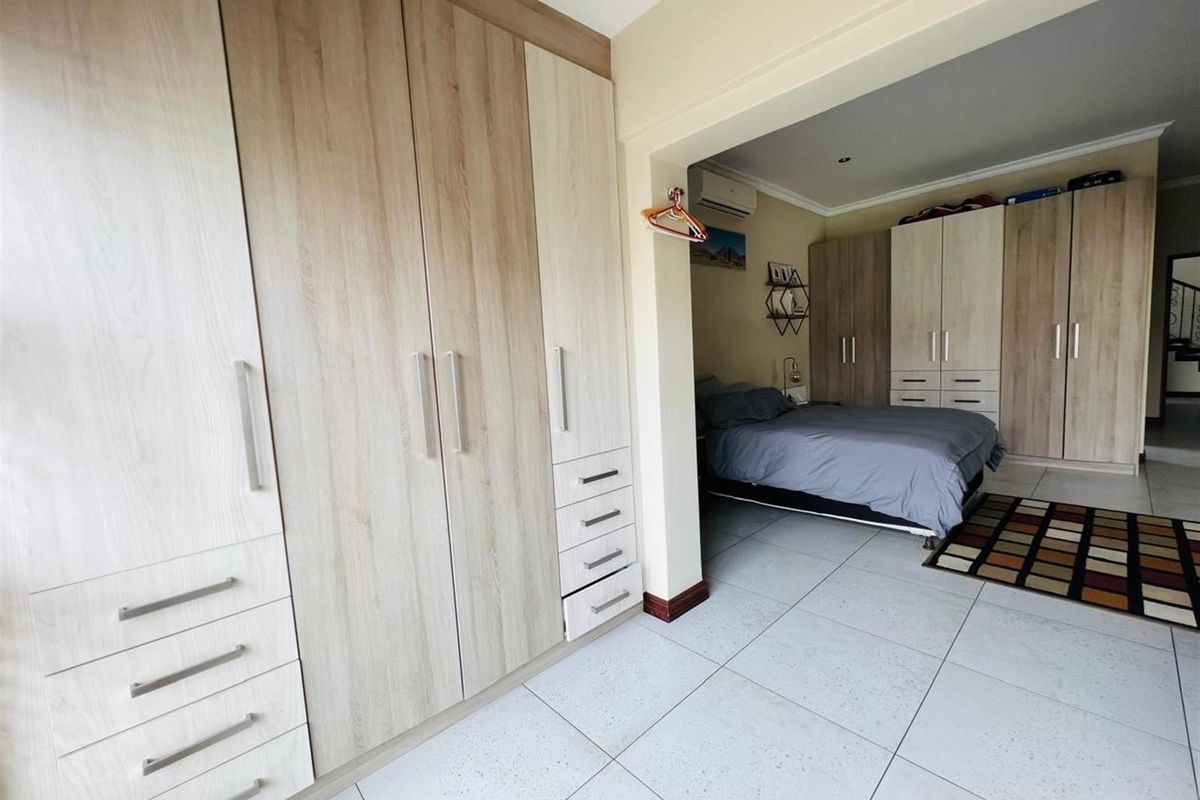 Spacious bedroom featuring extensive built-in cabinetry with a light wood finish, tiled flooring, and an integrated air conditioning unit.