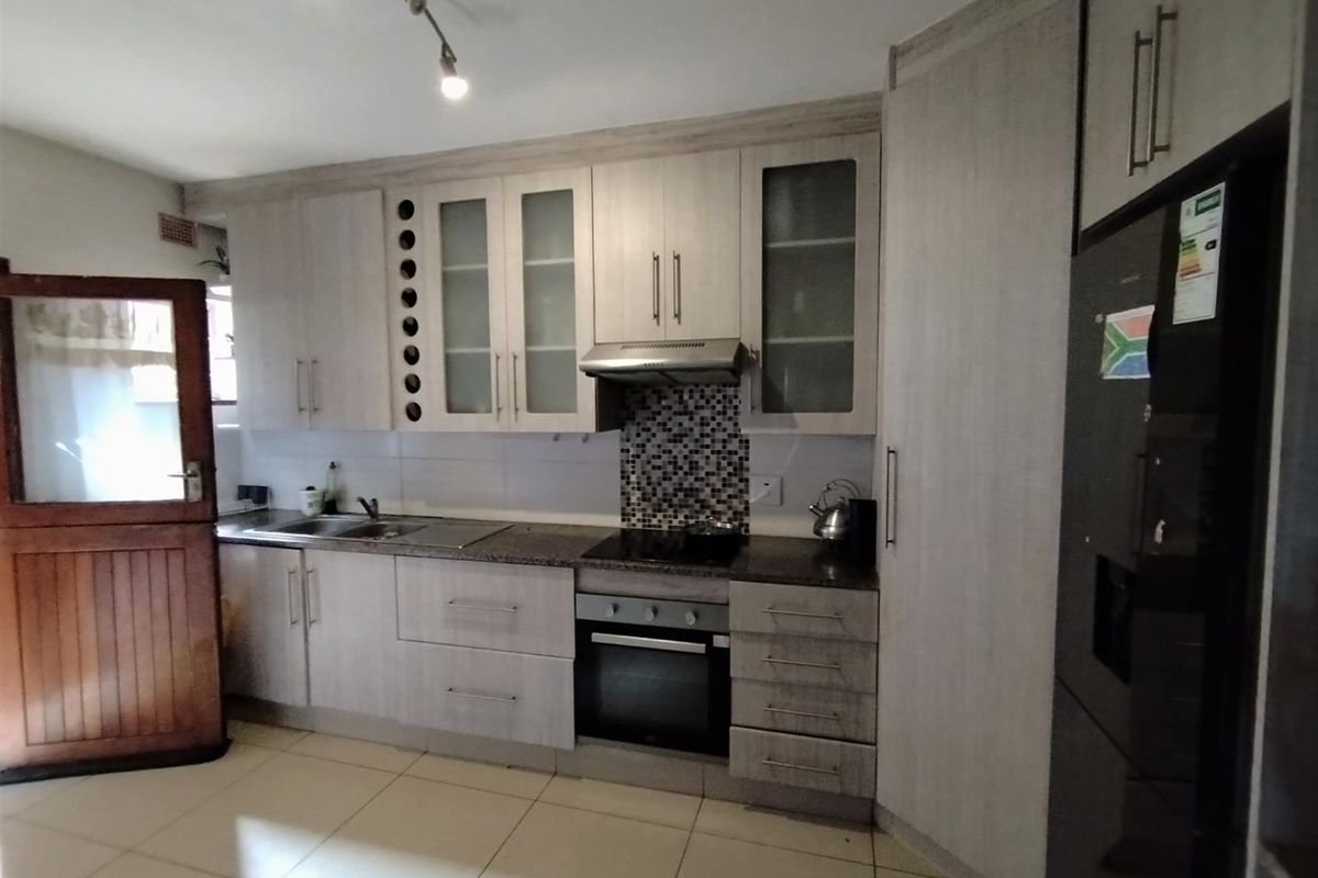 A functional kitchen featuring light wood-finish cabinetry, granite countertops, a mosaic tile backsplash, and integrated stainless steel appliances.