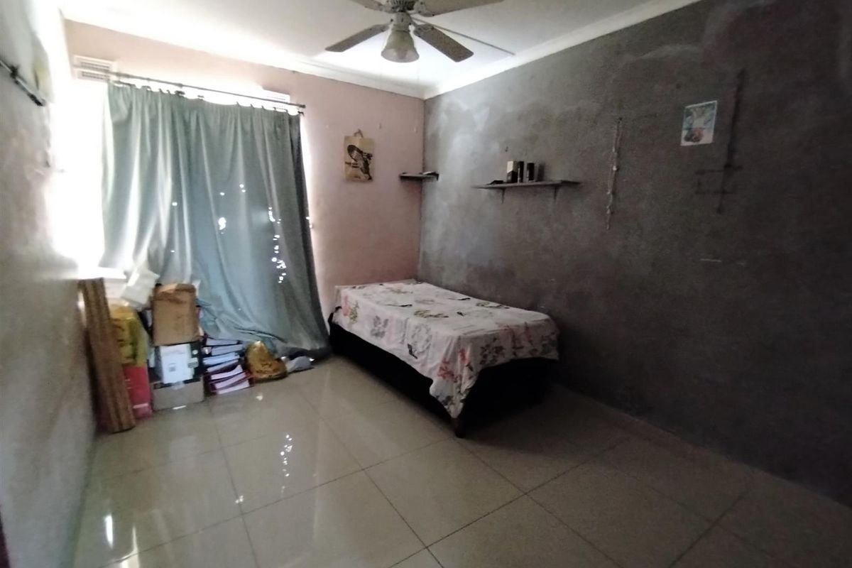 A bedroom featuring tiled flooring and a ceiling fan, currently requiring wall finishing and cosmetic updates to improve the overall aesthetic.