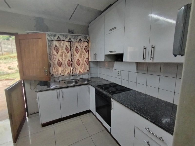 Compact kitchen featuring white cabinetry, granite countertops, and built-in appliances, requiring minor cosmetic repairs to walls and ceiling.