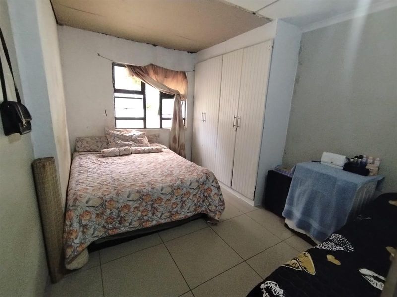A bedroom featuring tiled flooring and a built-in wardrobe, currently requiring cosmetic updates to the ceiling and wall finishes.
