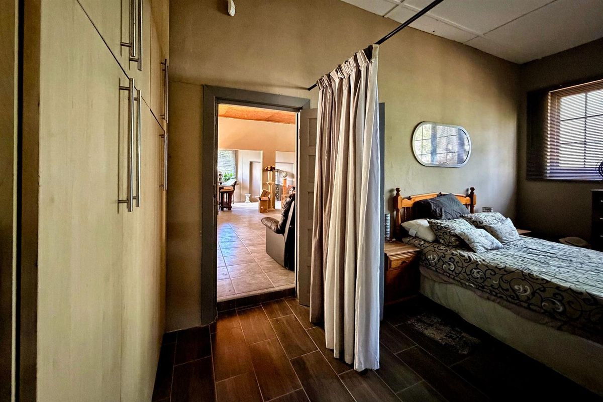 A bedroom featuring built-in cabinetry, tiled flooring, and a doorway leading to an adjacent living space.